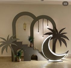 an artistic display with palm trees and other decorative items in the background, including a crescent shaped sculpture