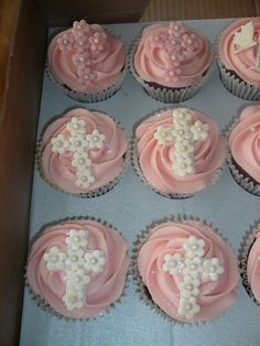 cupcakes with pink frosting and white decorations in a box