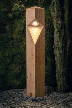 a wooden post with a light on it next to a tree