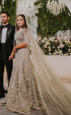 a man and woman standing next to each other in front of a flower covered wall