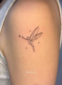 a woman's back shoulder with a small tattoo of a fairy tinkerbell