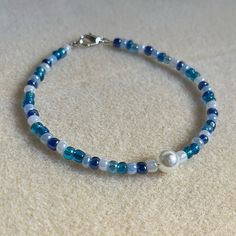 a blue and white beaded bracelet on carpeted surface with silver clasp closures