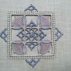 a close up of a cross stitch pattern on a piece of cloth with blue thread