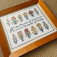 a cross - stitch sample in a wooden frame with the words, flowers of tomorrow are in the seeds of baby