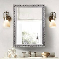 a bathroom sink with a mirror above it and lights on the wall next to it