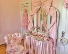 a room with pink furniture and decorations on the walls, including a dressing table set up