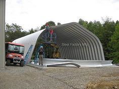 two men are working on the roof of a large metal structure that is being constructed