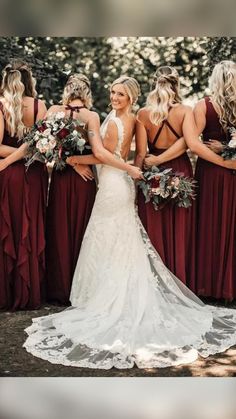 a group of women standing next to each other wearing red dresses and holding bouquets