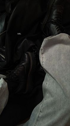 two pairs of black shoes are sitting on top of a pile of jeans and pants