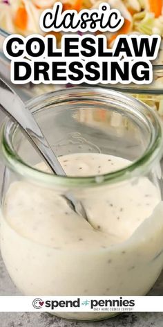 a glass jar filled with dressing sitting on top of a table next to a bowl of salad