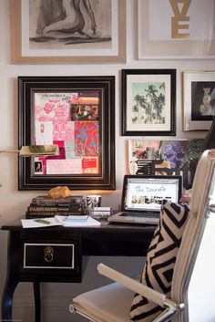 a desk with a laptop computer and pictures on the wall above it in a home office