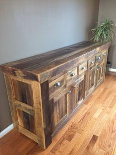 a large wooden cabinet sitting on top of a hard wood floor next to a potted plant