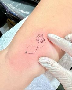 a dog paw tattoo on the left side of the right arm, with a line drawn across it