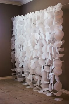 a room with a large white curtain made out of paper flowers on the side of it