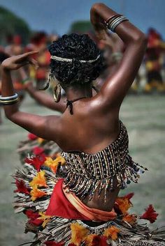 a woman in an elaborate dress dancing with feathers on her head and hands behind her back