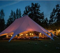 a large white tent is lit up at night