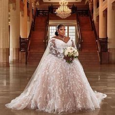 a woman in a wedding dress standing on the floor with her bouquet and looking at the camera