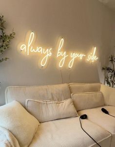 a white couch sitting under a neon sign that says always by your side