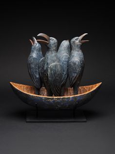 three birds sitting on top of a wooden boat in the shape of a boat with two smaller birds perched on it's sides