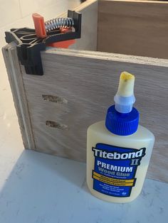 a bottle of glue sitting on top of a counter next to a piece of wood