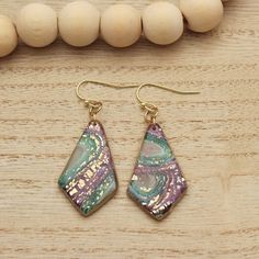 a pair of earrings sitting on top of a wooden table next to bead necklace