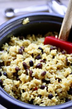 rice and beans are mixed together in a bowl with a wooden spoon on the side