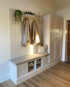 a room with white walls and wooden flooring, two coats hanging on the wall