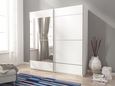 a white wardrobe with mirrored doors and drawers in a living room next to a window