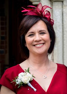 a woman in a red dress is smiling at the camera with a flower on her lapel