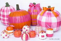 several pumpkins painted in different patterns and colors with bows on them, all lined up next to each other