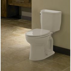 a white toilet sitting in a bathroom next to a wall mounted sink and cabinet with drawers