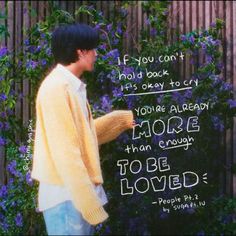 a young man standing in front of purple flowers with a bible verse written on it