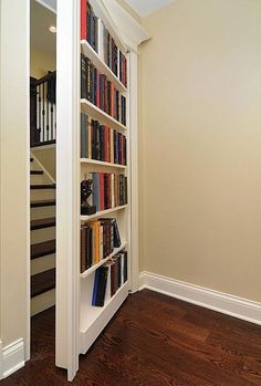 a bookshelf filled with lots of books next to a stair case in a home