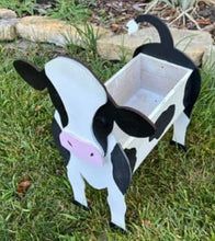 a cow shaped planter sitting in the grass