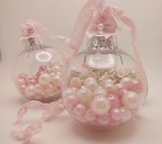 two glass ornaments with pink bows and pearls