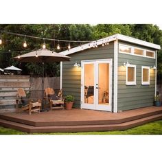 a small backyard shed with patio furniture and an umbrella over the door, on a deck