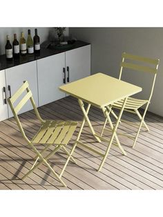 two yellow folding chairs and a table on a wooden floor in front of white cabinets