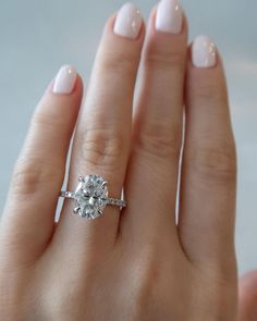 a woman's hand with a diamond ring on her left hand and a white manicure