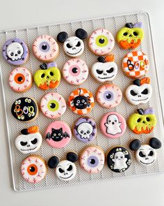 there are many decorated doughnuts on the tray and one is black, white, orange, and pink