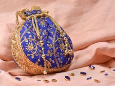 Blue Potli Bag with Pearl Handle Strap With its classy zari work and a pearl handle strap all in gold this Blue Potli Bag is ideal for this wedding season. Fabric Raw Silk Color Royal Blue Embroidery Zari Work in Gold Size amp Dimensions Height - 8 inWidth - 7.5 inDepth - 1.5 in Strap Pearl Handle Strap Closure Tasseled Drawstring Compartments Single compartment Care Wipe with a soft clean amp dry cloth to remove dust When not in use store it in a dust bag for longer product life Avoid liquid ex Festive Gift Potli Bag, Bollywood Style Gold Shoulder Bag With Zari Work, Gold Zari Work Bag For Diwali, Gold Bag With Zari Work For Diwali, Gold Bags With Zari Work For Diwali, Traditional Gold Shoulder Bag For Diwali, Festive Traditional Potli Bag, Festive Party Potli Bag With Openable Detail, Elegant Festive Openable Potli Bag