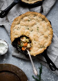 a pie with a spoon in it on top of a table next to other dishes