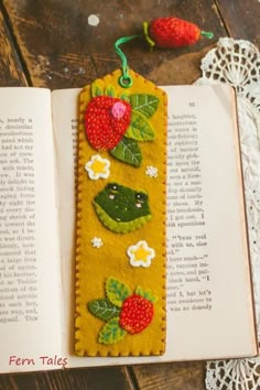 the bookmark is decorated with strawberries and green leaves on yellow fabric, along with lace doily