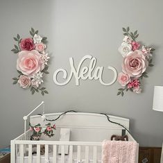 a baby's room decorated in pink and gray with flowers on the wall above it