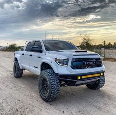 a white truck parked on top of a dirt road