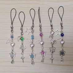 six different colored charms are hanging on a wooden surface with black string and silver clasps