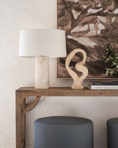 a table with two stools and a painting on the wall behind it in a living room