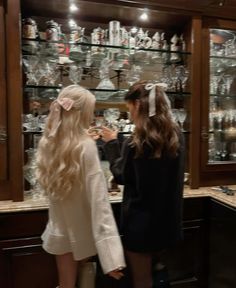 two women standing in front of a display case