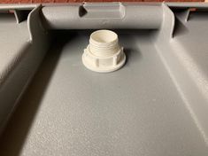 a white plastic cup sitting on top of a gray table next to a red brick wall