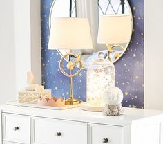 a white dresser topped with a mirror and two lamps