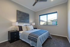 a bedroom with a bed, nightstands and ceiling fan in front of a window